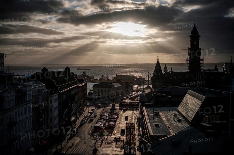 A cityscape at sunset with silhouettes of buildings and clouds overhead and looking out to the Oresund Strait, between Sweden and Denmark, as seen from Helsingborg, Sweden, Scandinavia, Northern Europe