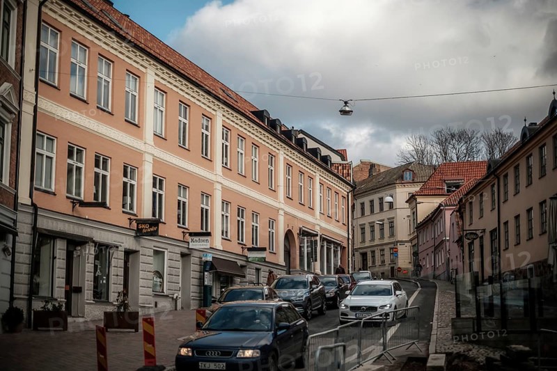 City street with parked cars and pastel-colored buildings under a cloudy sky in Helsingborg, Sweden, Scandinavia