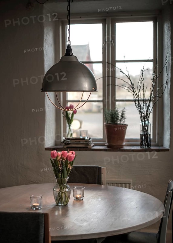 A cozy table setting with tulips and a soft glow from a pendant light, framed by a window in Helsingborg, Sweden, Scandinavia