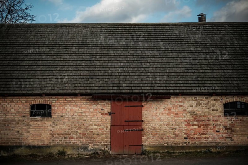 A rustic brick building with a red door under an overcast sky, featuring a chimney in Helsingborg, Sweden, Scandinavia