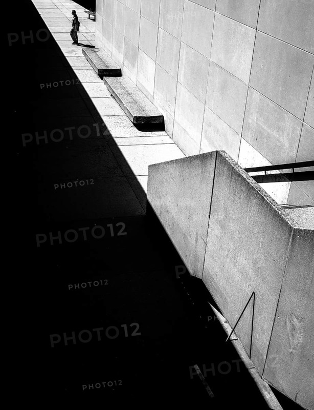 Geometric black and white scene with sharp shadows and a solitary person against a wall in Toronto, Ontario, Canada, North America