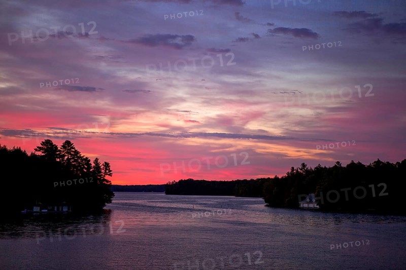 A peaceful sunset paints the sky in vibrant colors over a calm lake in Muskoka, Ontario, Canada, North America
