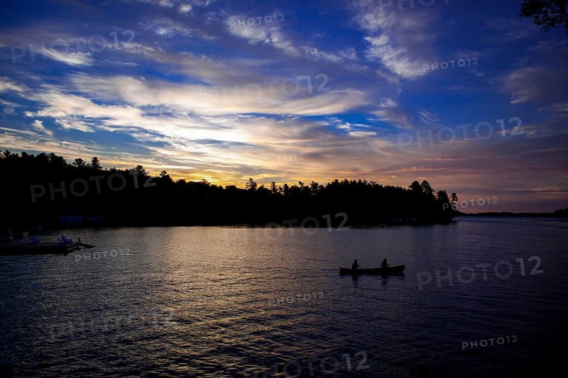 Silhouettes of two canoes on a lake at sunset, creating a peaceful landscape in Muskoka, Ontario, Canada, North America