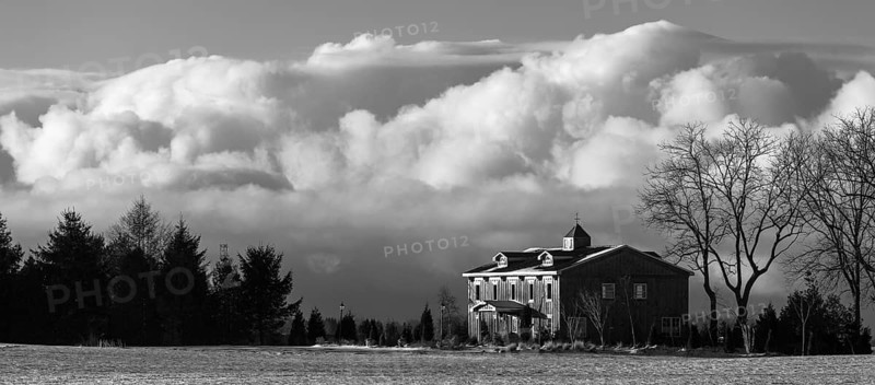 Monochrome image featuring a house against a backdrop of billowing clouds, evoking a serene winter scene in St. Thomas, Ontario, Canada, North America