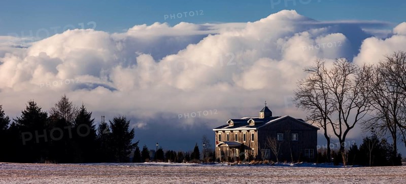 Color image of a house with large clouds in the background, set in a tranquil winter landscape in St. Thomas, Ontario, Canada, North America