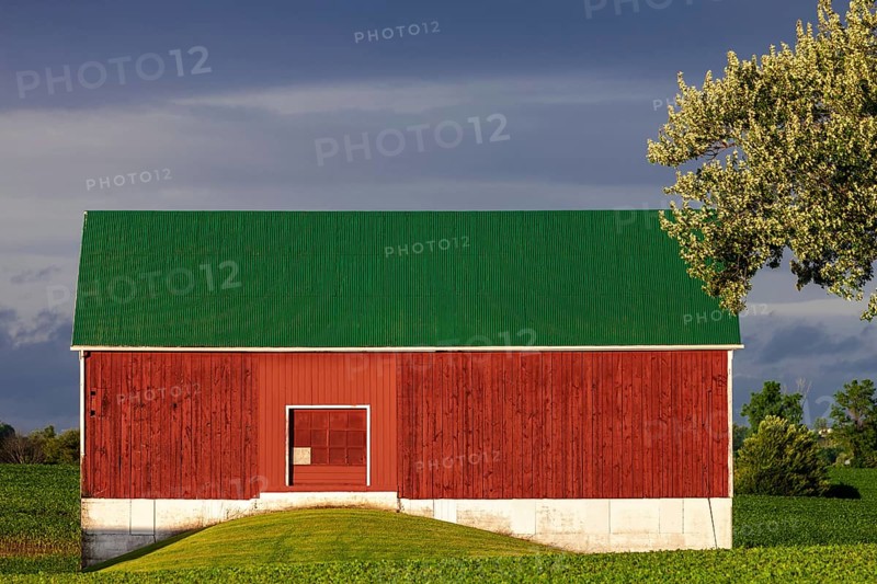 A red barn with a green roof against a cloudy sky in St. Thomas, Ontario, Canada, North America