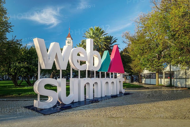 Nov 6, 2024 - Lisbon, Portugal: Big Web Summit sign displayed outdoors in park with lush palm trees on sunny day clear blue skies. Major technology conference, internet technology, emerging technology, marketing, AI solution, spirit of innovation
