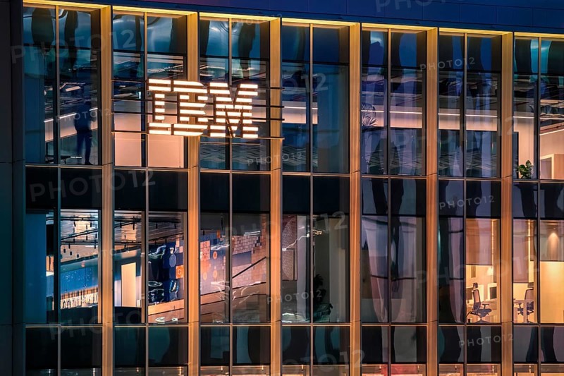 Jan 15, 2025 - Lisbon, Portugal: Nighttime view of IBM office building with glowing logo and sleek glass exterior. Illuminated interior spaces and reflections, innovative spirit and global presence of renowned technology corporation, corporate life