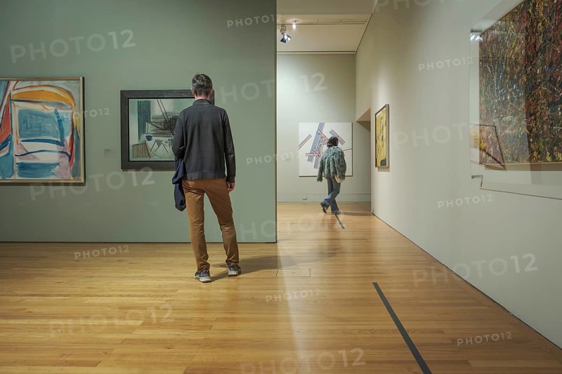 Jan 13, 2024 - Lisbon, Portugal: two visitors explore abstract artworks displayed on walls of Centro Cultural de Belem known as Berardo Museum, Lisbon, Portugal. One person contemplating contemporary artwork, other walking further into gallery