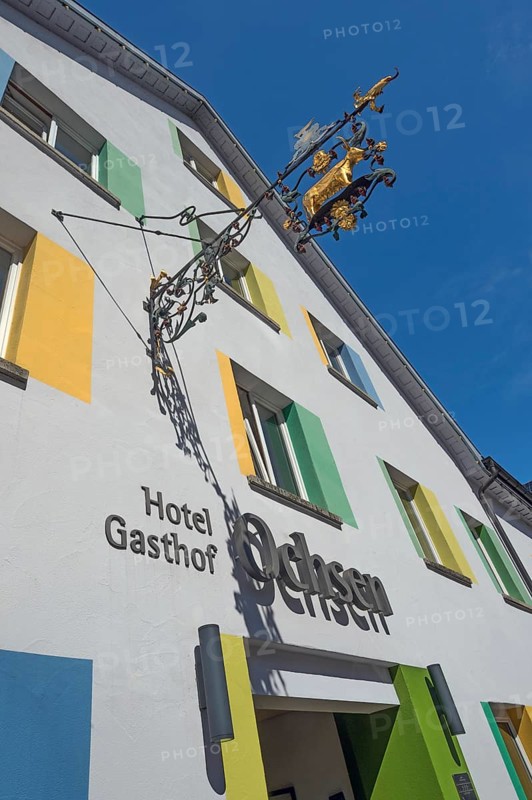 Blue sky, Hotel-Gasthof-Ochsen with nose sign and colourful windows in Kisslegg, Allgäu, Baden-Württemberg, Germany