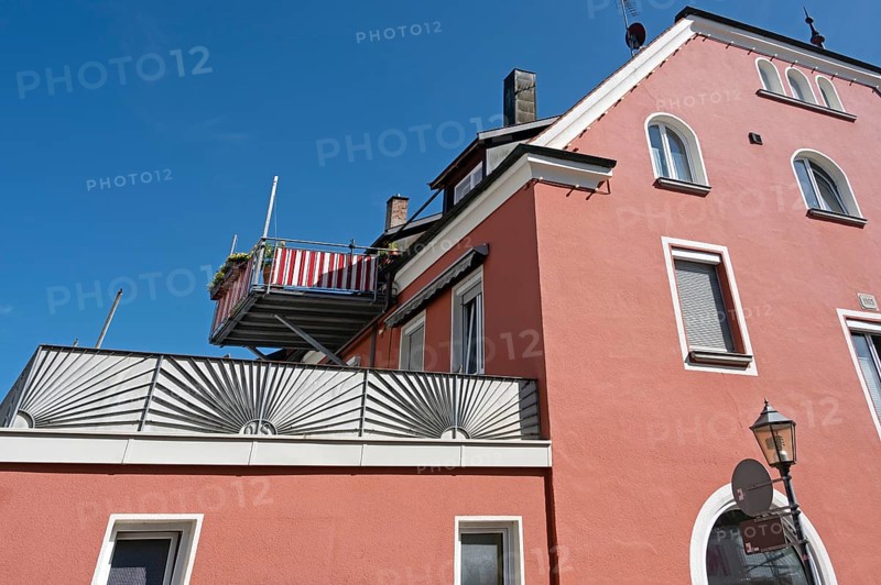 Blue sky, red façade with dormers, chimneys and balcony in Kisslegg, Allgäu, Baden-Württemberg, Germany