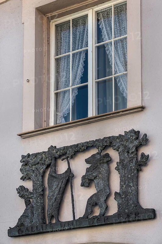 Window with blinds and metal relief, Gallus and the bear on the façade of the pharmacy in Kisslegg, Allgäu, Baden-Württemberg, Germany