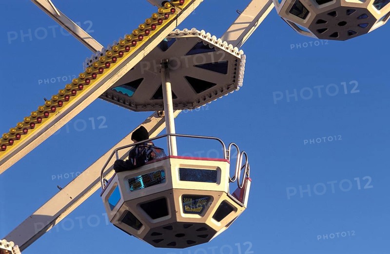 A geometric gondola of a Ferris wheel against a clear blue sky at an amusement park