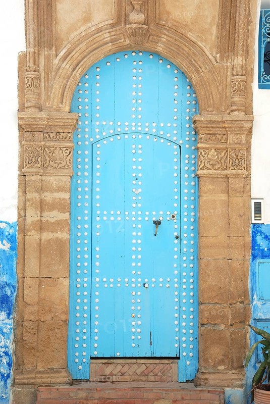 An ancient blue door with an ornate stone archway, featuring a weathered look in a historical structure. Rabat Kasbah des Oudeïas in Marocco
