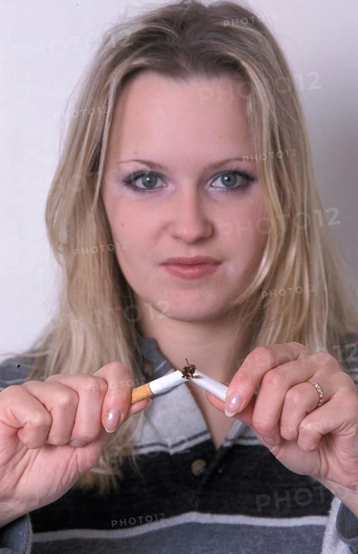 A woman breaks a cigarette in half, symbolizing quitting smoking with a determined look