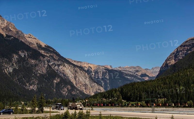 Mountain pass with highway and vehicles, surrounded by forest as viewed from the Trans Canada Highway in British Columbia, Canada, North America