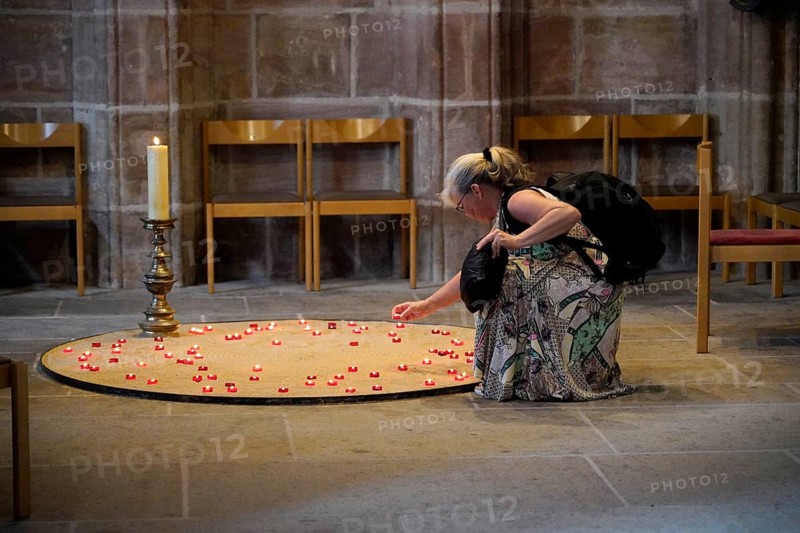 Woman lighting candles in a quiet church room, surrounded by chairs, St Lorenz Church, Nuremberg, Middle Franconia, Franconia, Bavaria, Germany