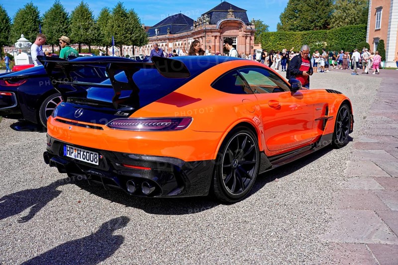 Oldtimer Classic, Gala International Concours d'Elegance Schwetzingen 2025, Germany, Europe, An orange sports car with rear wing in front of a historic building and sky