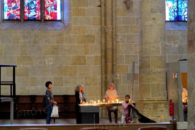 The interior of the largest Protestant church in Germany. It has the world's tallest church tower, Ulm Minster, Germany, Europe, Peaceful scene in the cathedral with people lighting candles in front of a stained glass window, Ulm