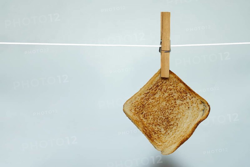 Toasted bread hanging on clothesline with clothespin against white background