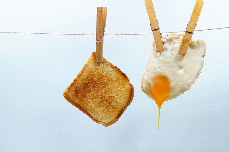 Toast and fried egg hanging from a clothesline with clothespins, representing a simple and unconventional breakfast