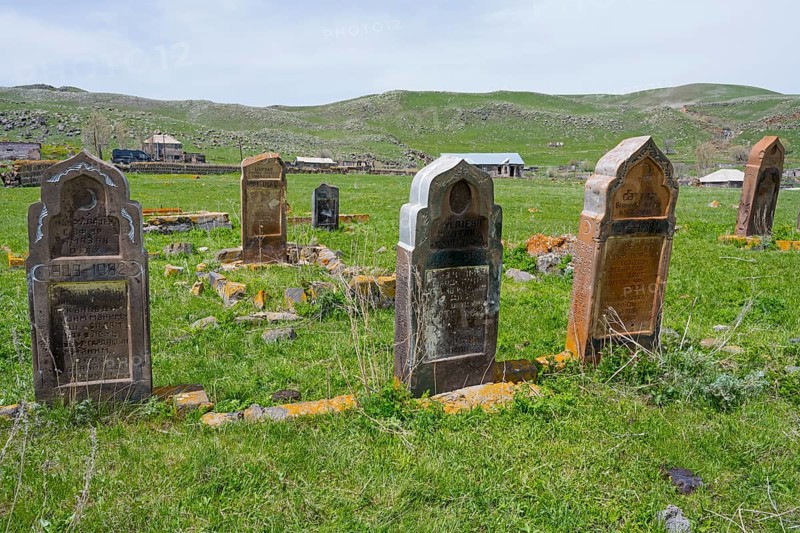 Cemetery with old weathered gravestones on green grassland with rolling hills in the background, old cemetery, Aghvorik, Shirak province, Armenia