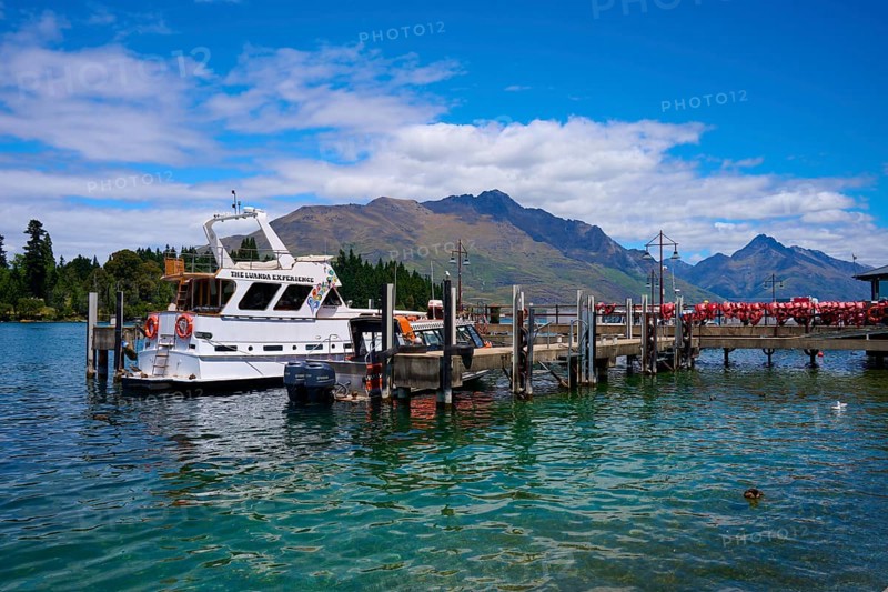 Boat at a jetty on a tranquil lake with surrounding mountain scenery, Queenstown, Queenstown-Lakes District, Otago, South Island, New Zealand