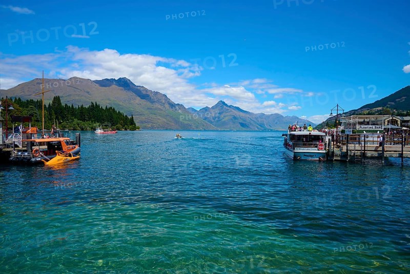 Boats on a jetty with a view of the surrounding mountains and blue water, Queenstown, Queenstown-Lakes District, Otago, South Island, New Zealand