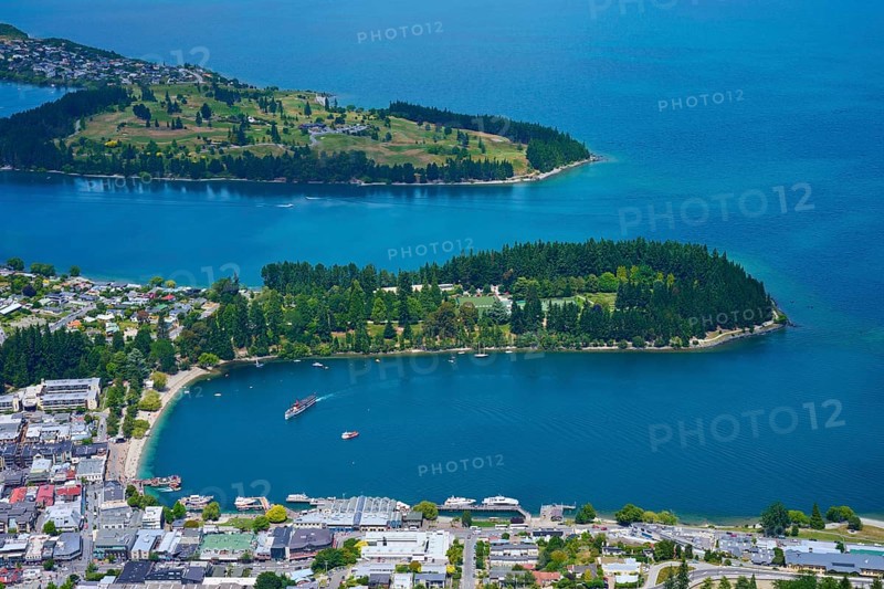 Aerial view of an urban landscape with a blue-green lake and forested peninsulas, Queenstown, Queenstown-Lakes District, Otago, South Island, New Zealand