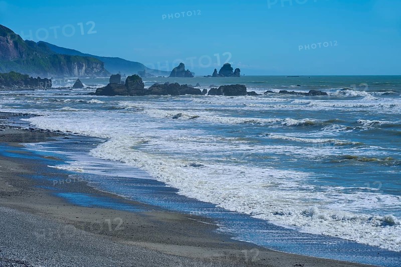 Stormy waves crash against an unspoilt coastline with striking rock formations, West Coast, South Island, New Zealand