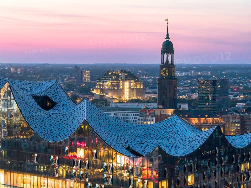 Aerial view of the Elbphilarmonie with St Michael's Church and Hamburg Bunker in the background at blue hour, Hamburg, Germany