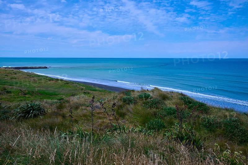 White sandy beach with grassy coastline and gentle waves under a cloudy sky, Mana Bay, Riverview Lookout, Patea, Taranaki, North Island, New Zealand
