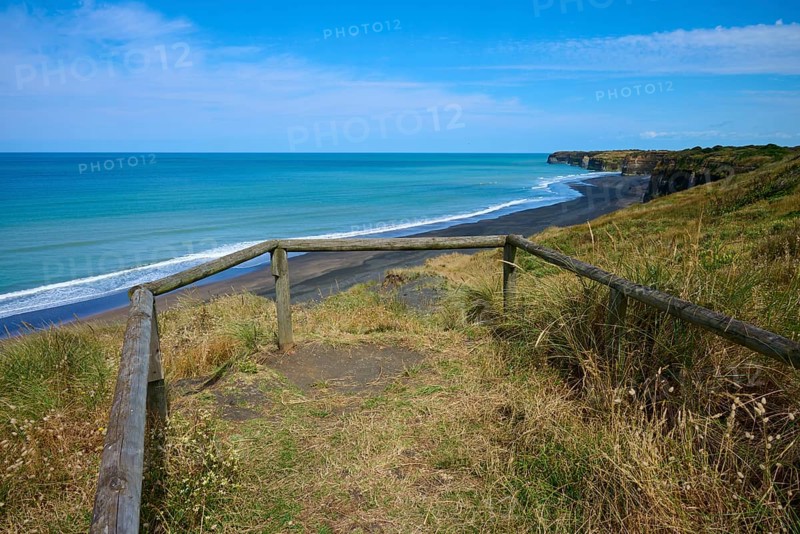 Viewing platform with wooden railing overlooks black sand beach and cliffs on a quiet coast, Mana Bay, Riverview Lookout, Patea, Taranaki, North Island, New Zealand