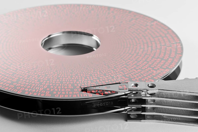 Detail shot of a separated hard disk platter with actuator arm in light grey backAllegory theme regarding operation systems
