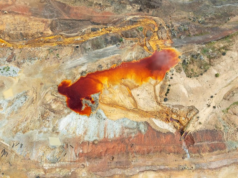 Old mining site and deep orange-red hues in the water of a pool in the mineral-rich area of the Rio Tinto mines. The colour is caused by oxidised iron minerals. Aerial view. Drone shot. Huelva province, Andalusia, Spain