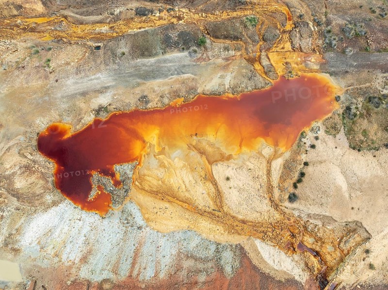 Deep orange-red hues in the water of a pool in the mineral-rich area of the Rio Tinto mines. The colour is caused by oxidised iron minerals. Aerial view. Drone shot. Huelva province, Andalusia, Spain