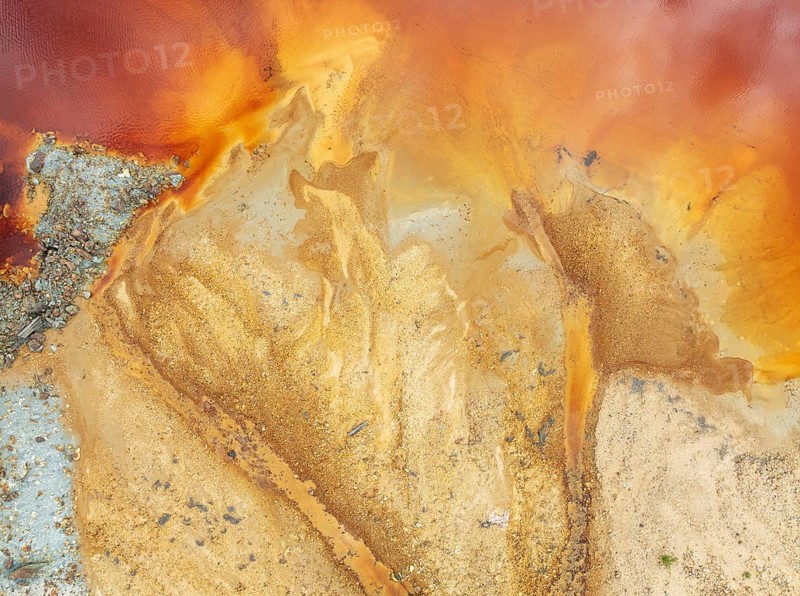 Abstract patterns in a pool in the mineral-rich area of the Rio Tinto mines. The colour is caused by oxidised iron minerals. Aerial view. Drone shot. Huelva province, Andalusia, Spain
