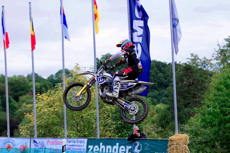 Motocross, Rudersberg, Baden-Württemberg, Germany, Europe, Motocross rider jumps with motorbike in front of flags. Green landscape in the background, Rudersberg motocross