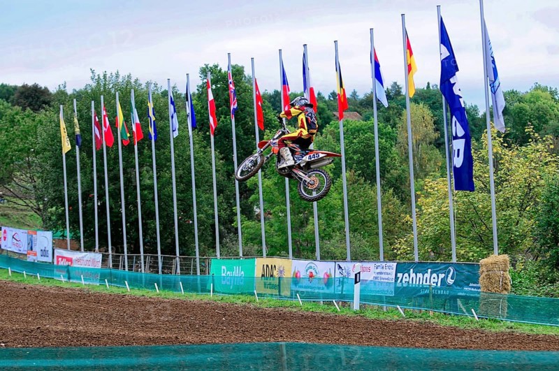 Motocross, Rudersberg, Baden-Württemberg, Germany, Europe, A motorcyclist jumps into the air while numerous flags fly in the background, Rudersberg Motocross