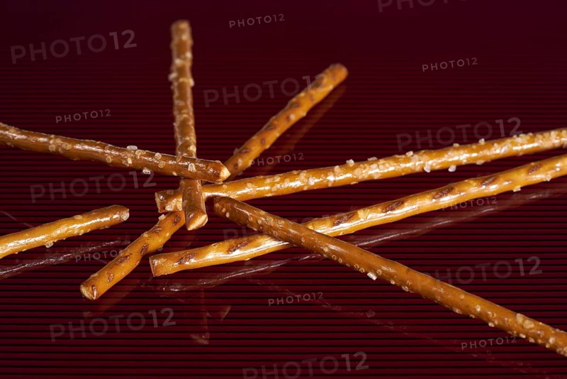Closeup of some salt sticks on dark red striped glossy ground
