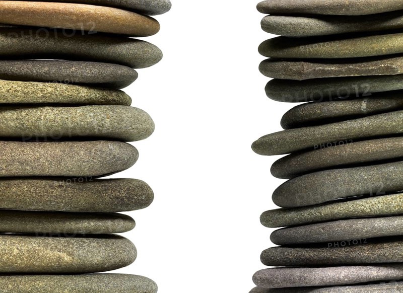 Low angle view of two flat pebble stone stacks in light back