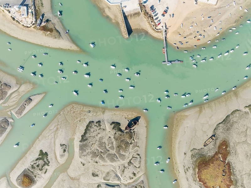 Fishing boats at low tide at the fishing village of Sancti Petri. In the marshland of the Bahía de Cádiz Nature Reserve. Aerial view.. Drone shot. Cádiz province, Andalusia, Spain
