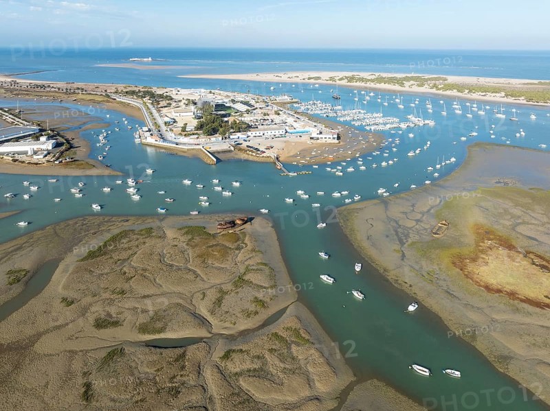 Network of channels and streams at low tide and the fishing village of Sancti Petri at the Atlantic Ocean. In the marshland of the Bahía de Cádiz Nature Reserve. Aerial view.. Drone shot. Cádiz province, Andalusia, Spain