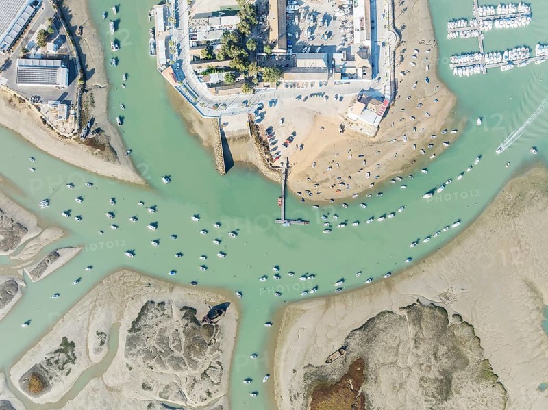 Fishing boats at low tide at the fishing village of Sancti Petri. In the marshland of the Bahía de Cádiz Nature Reserve. Aerial view.. Drone shot. Cádiz province, Andalusia, Spain
