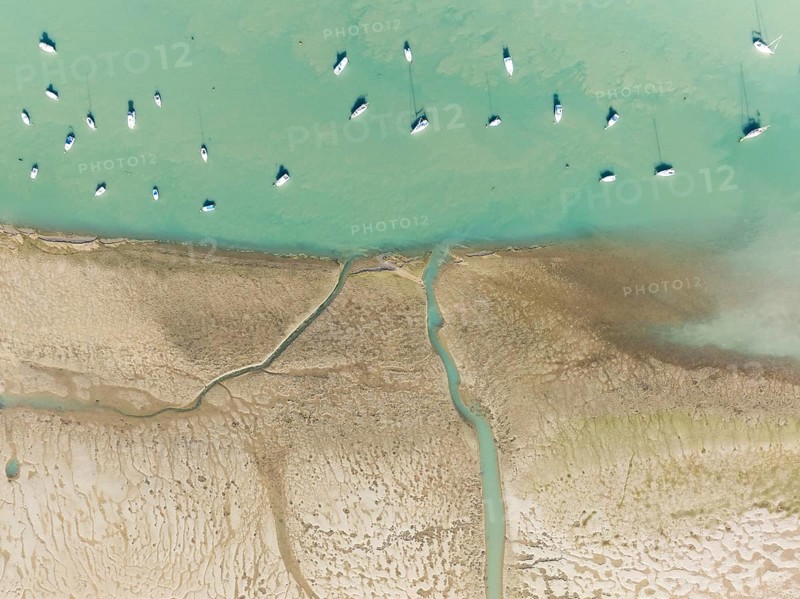 Sports and fishing boats at low tide near the fishing village of Sancti Petri. In the marshland of the Bahía de Cádiz Nature Reserve. Aerial view.. Drone shot. Cádiz province, Andalusia, Spain