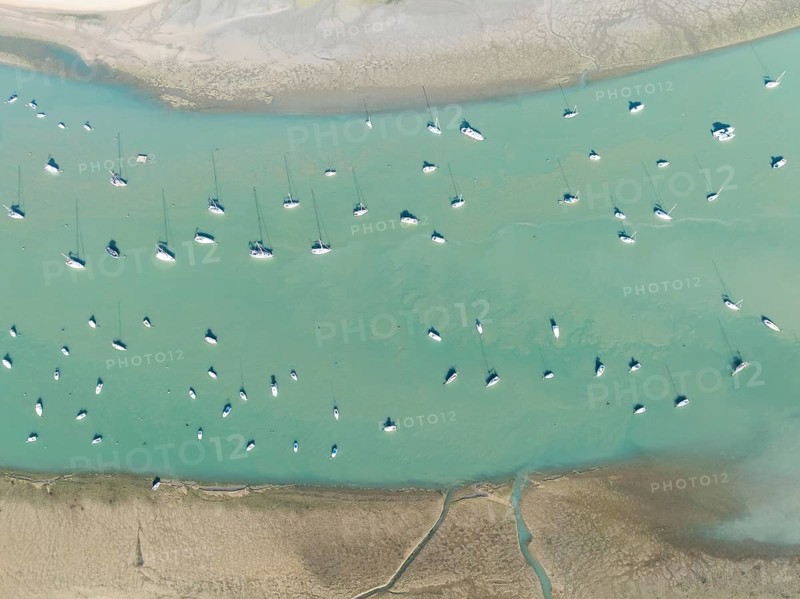 Sports and fishing boats at low tide near the fishing village of Sancti Petri. In the marshland of the Bahía de Cádiz Nature Reserve. Aerial view.. Drone shot. Cádiz province, Andalusia, Spain