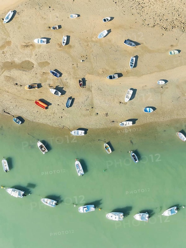 Fishing boats at low tide at the fishing village of Sancti Petri. In the marshland of the Bahía de Cádiz Nature Reserve. Aerial view.. Drone shot. Cádiz province, Andalusia, Spain