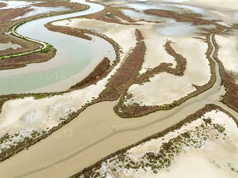 The Barbate river and surrounding marshland at low tide. Nature Reserve La Breña y Marismas del Barbate. Aerial view. Drone shot. Cádiz province, Andalusia, Spain