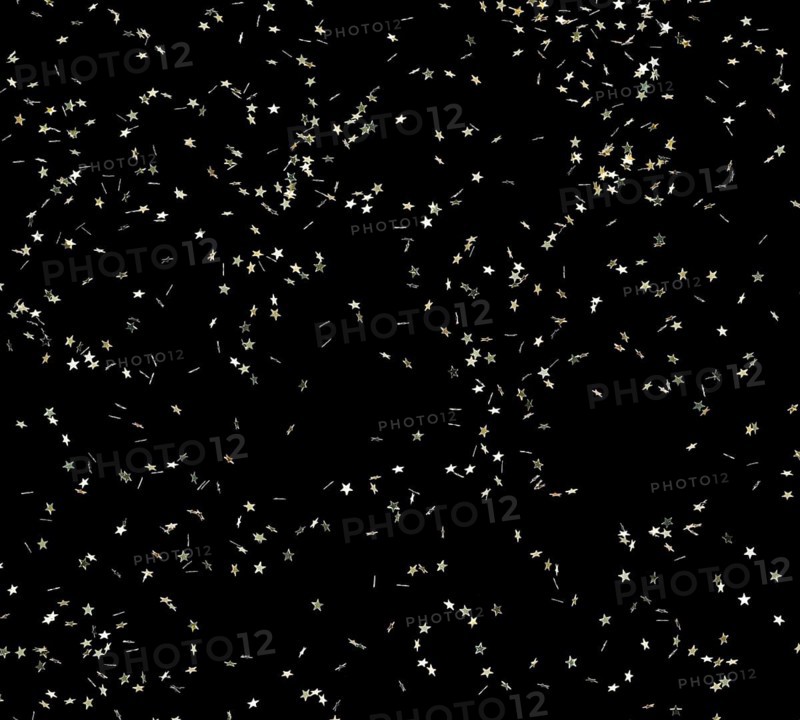 Punched small metallic stars falling in front of black back