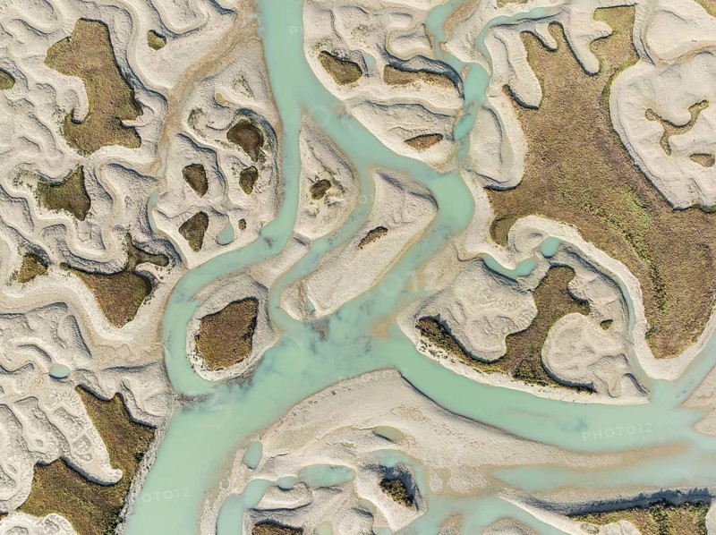 Network of channels and streams at low tide. In the marshland of the Bahía de Cádiz Nature Reserve. Aerial view. Drone shot. Cádiz province, Andalusia, Spain